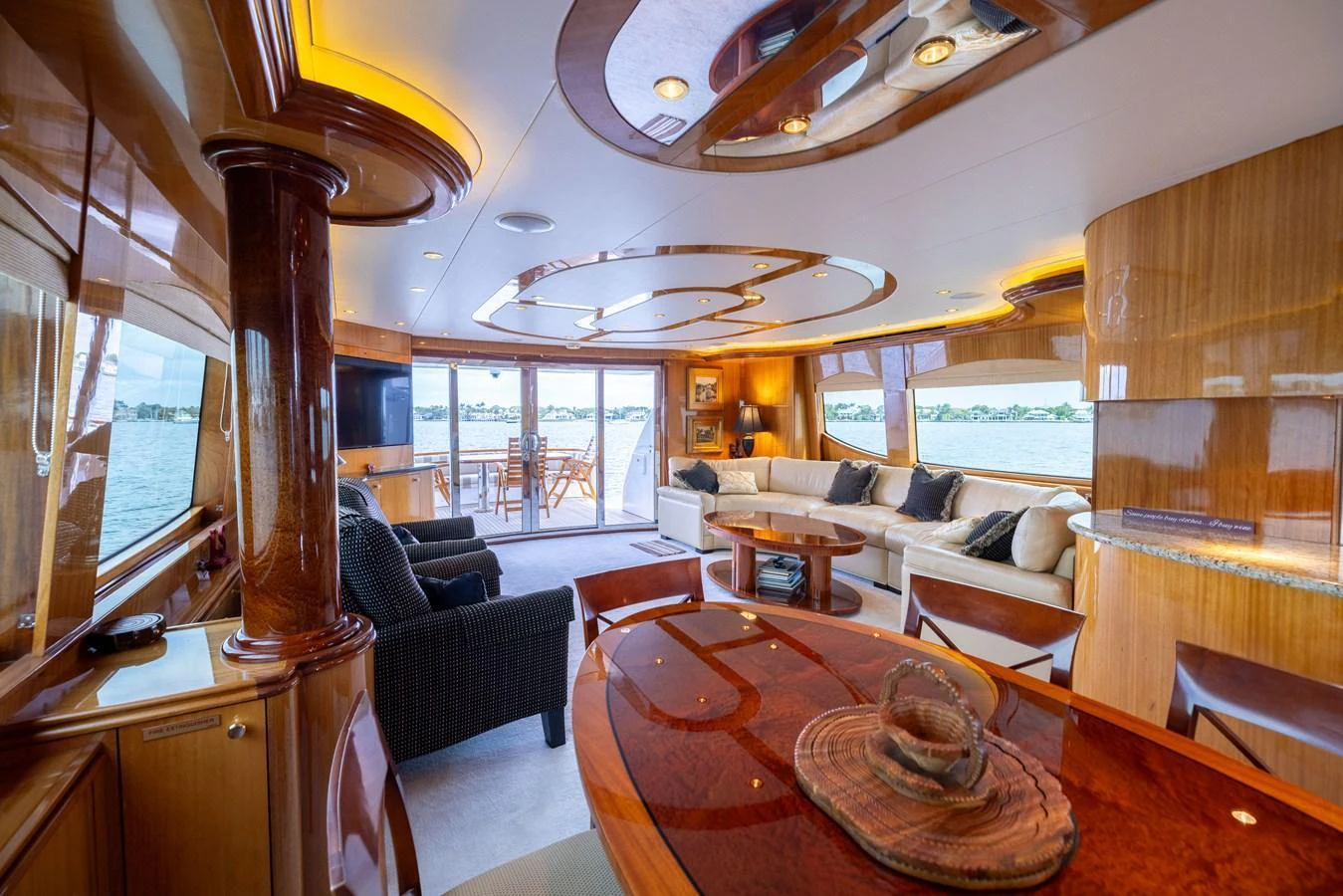 The salon features luxurious seating, elegant wood finishes, and expansive windows offering stunning views. aboard OUTRAGEOUS Yacht for Sale