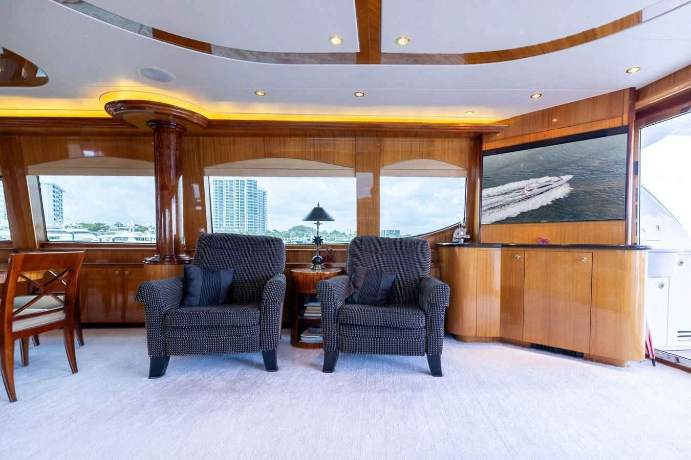 The yacht's interior features a cozy seating area with plush armchairs and elegant wood paneling. aboard OUTRAGEOUS Yacht for Sale