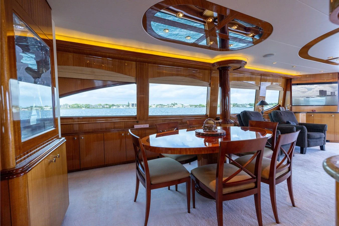 The yacht's dining area features elegant wooden furnishings and large windows offering scenic views. aboard OUTRAGEOUS Yacht for Sale