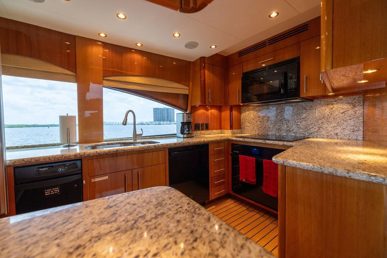The yacht's galley features sleek wooden cabinetry, granite countertops, and modern appliances, offering a luxurious and functional cooking space. aboard OUTRAGEOUS Yacht for Sale