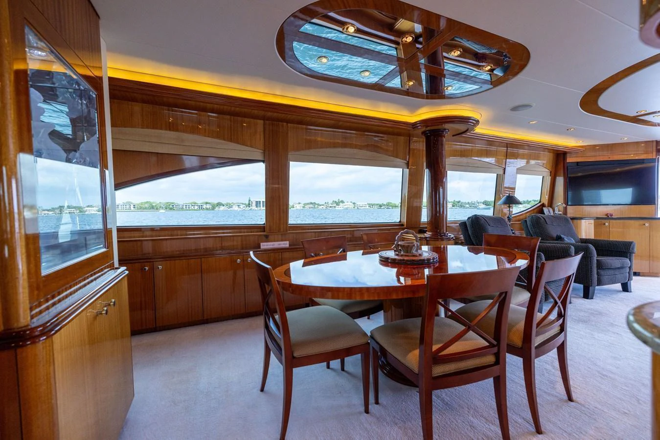 The yacht's dining area features elegant wooden furnishings and large windows offering scenic views. aboard OUTRAGEOUS Yacht for Sale