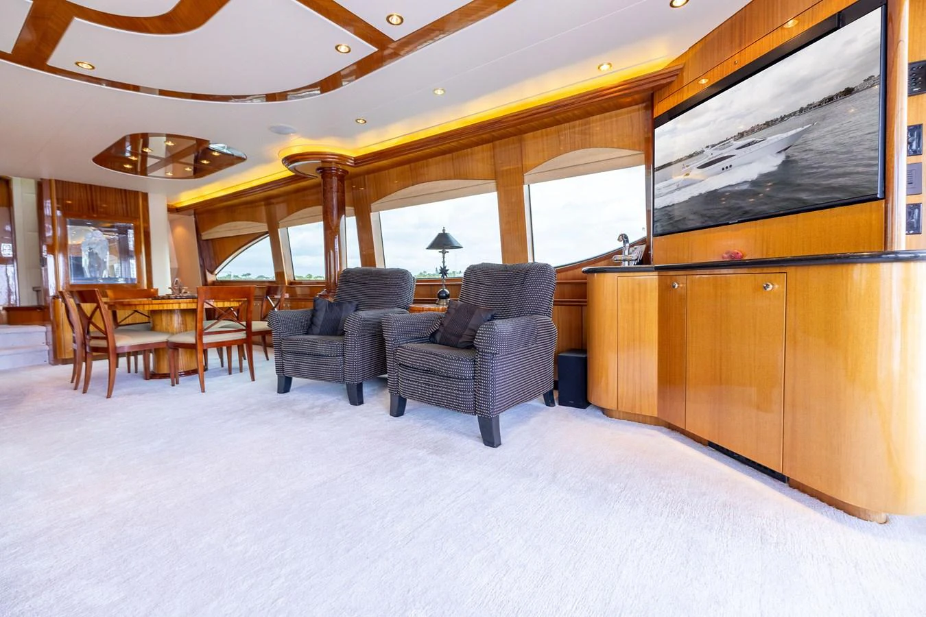 The yacht's interior features a spacious and elegantly designed living area with plush seating and a large window offering scenic views. aboard OUTRAGEOUS Yacht for Sale