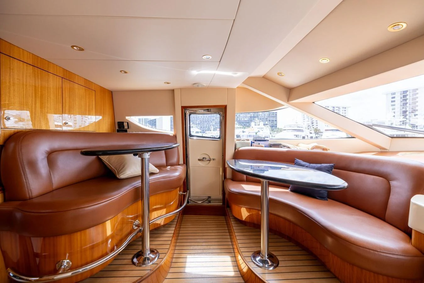 The yacht's interior features a cozy seating area with plush leather couches and polished wooden finishes, offering a comfortable and stylish space for relaxation. aboard OUTRAGEOUS Yacht for Sale