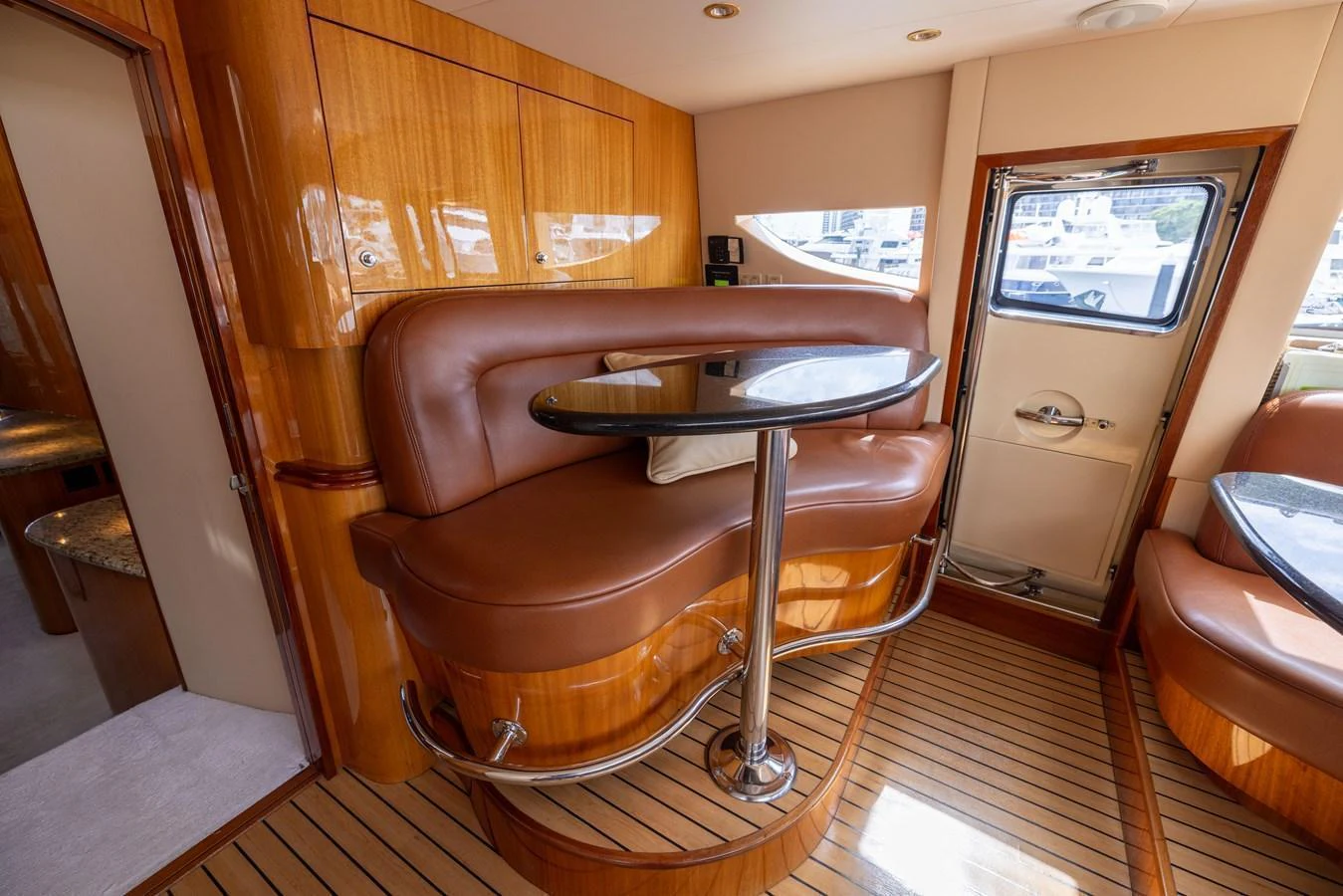 The salon features a cozy seating area with a polished wooden table and luxurious leather upholstery. aboard OUTRAGEOUS Yacht for Sale