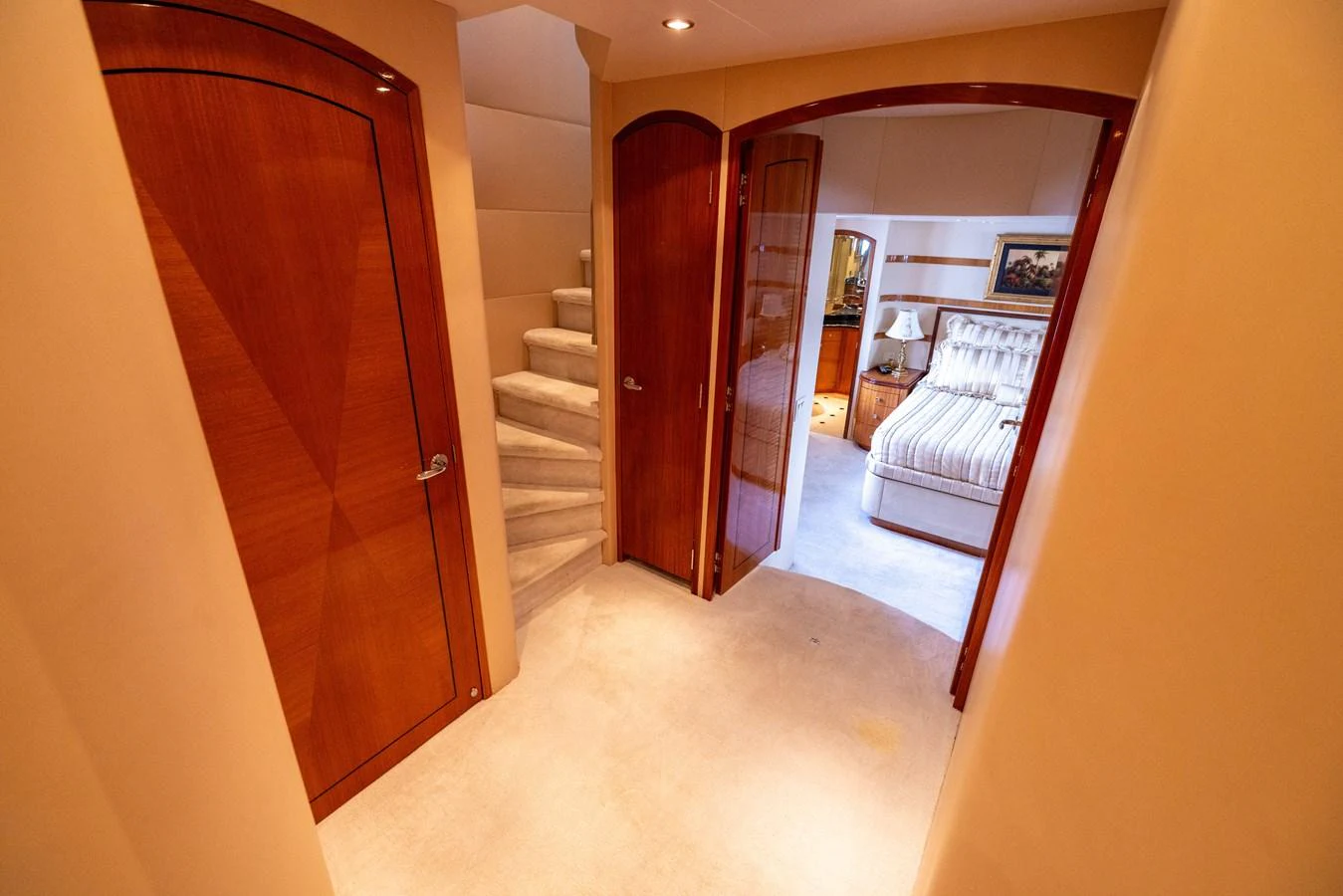 A warm and inviting hallway leads to a cozy stateroom with plush bedding. aboard OUTRAGEOUS Yacht for Sale