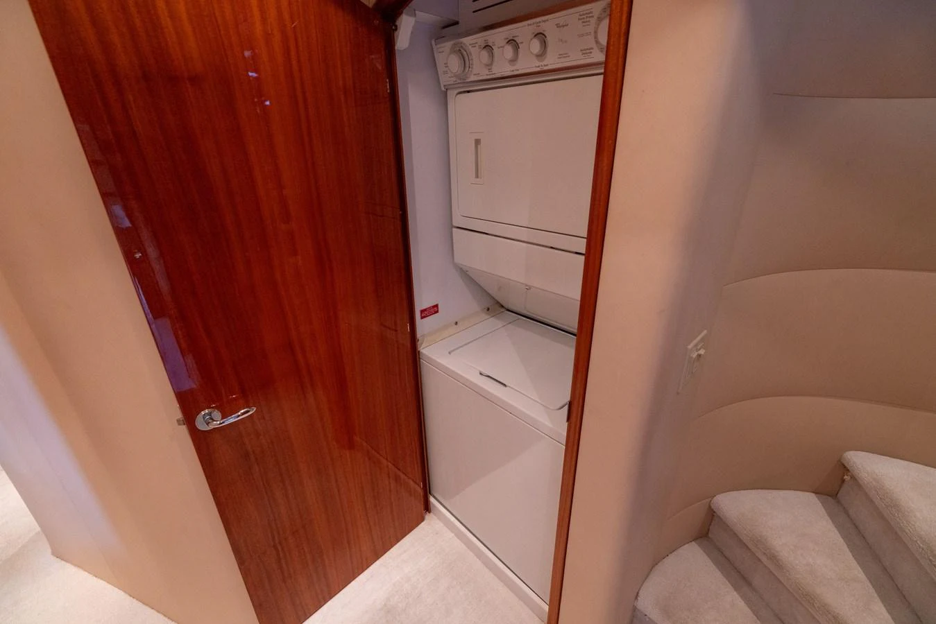 The yacht features a compact and efficient laundry area with a stacked washer and dryer. aboard OUTRAGEOUS Yacht for Sale