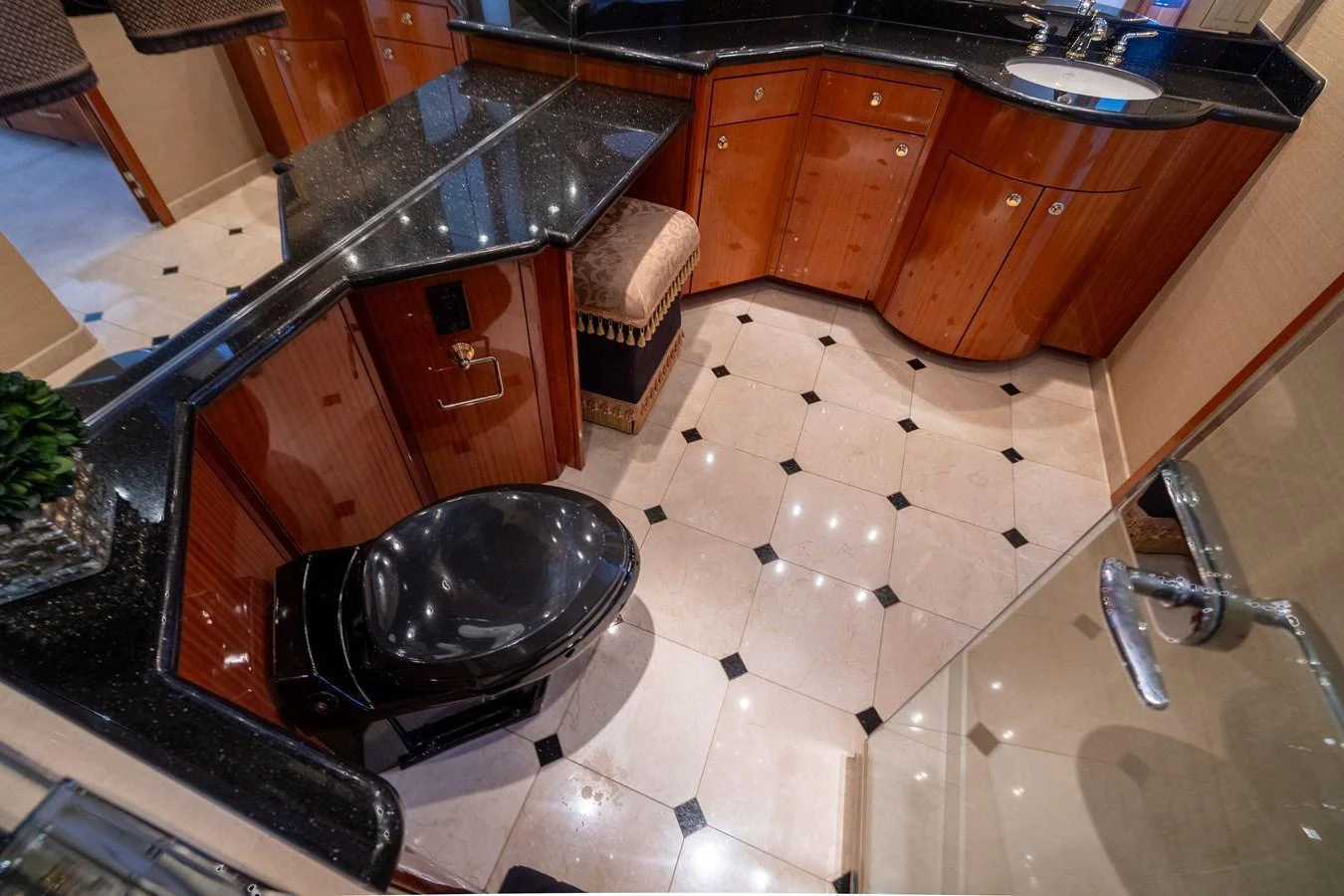 The yacht's bathroom features elegant wood cabinetry, a sleek black toilet, and a polished black countertop. aboard OUTRAGEOUS Yacht for Sale