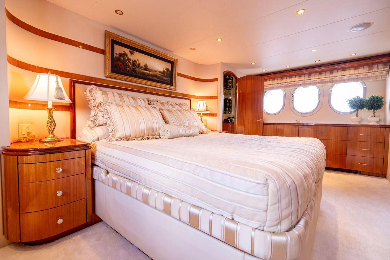 The master stateroom features a luxurious bed with elegant bedding, warm wood finishes, and ample natural light from large windows. aboard OUTRAGEOUS Yacht for Sale