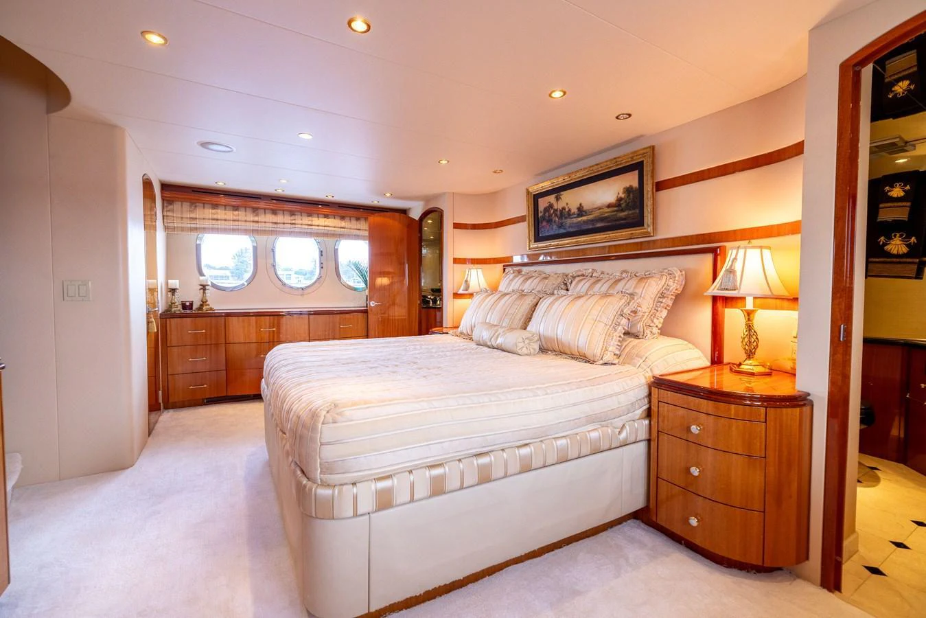 The master stateroom features a luxurious bed, elegant wood finishes, and ample natural light. aboard OUTRAGEOUS Yacht for Sale