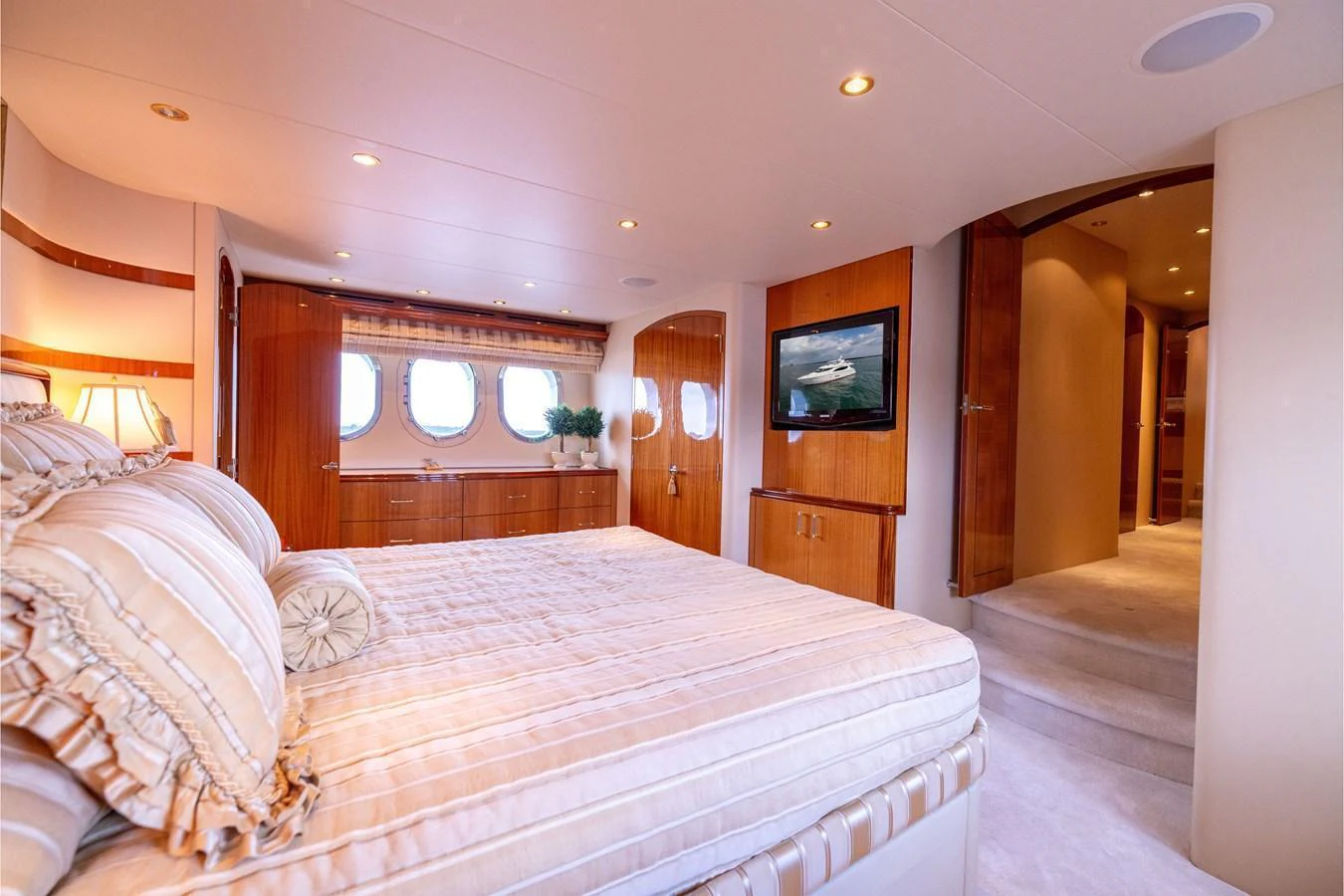 The master stateroom features luxurious bedding, warm wood finishes, and ample natural light. aboard OUTRAGEOUS Yacht for Sale