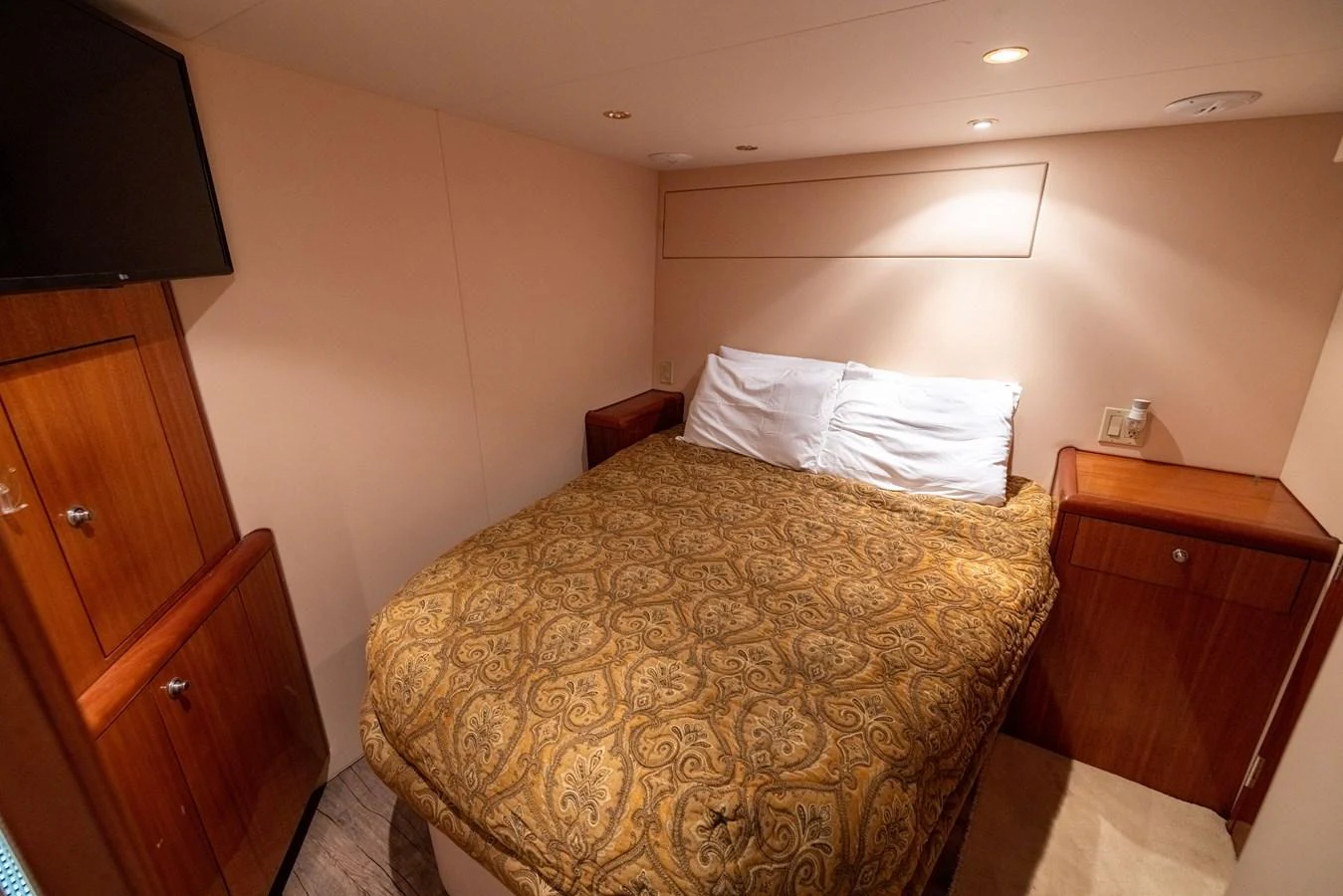 A cozy stateroom with a double bed and warm wooden cabinetry. aboard OUTRAGEOUS Yacht for Sale