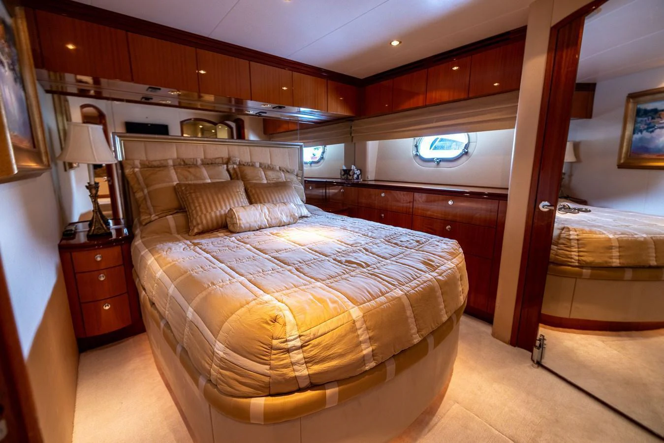 A luxurious stateroom featuring a plush bed, wooden cabinetry, and soft lighting. aboard OUTRAGEOUS Yacht for Sale