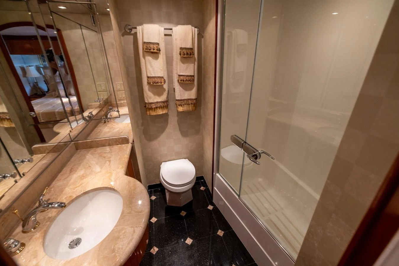 A luxurious yacht bathroom featuring a marble countertop, a toilet, and a glass-enclosed shower. aboard OUTRAGEOUS Yacht for Sale