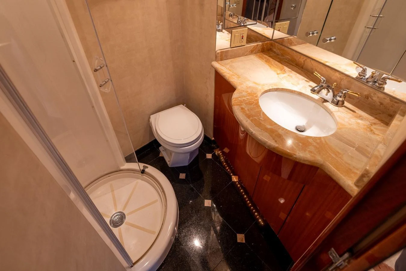 The yacht's bathroom features a compact shower, toilet, and elegant sink area. aboard OUTRAGEOUS Yacht for Sale