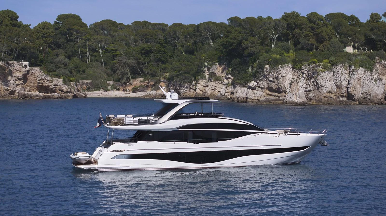 A sleek and modern yacht cruising along a scenic coastline with lush greenery and rocky cliffs. aboard POLARIS Yacht for Sale