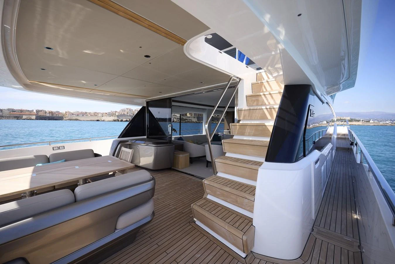 The aft deck features a spacious seating area and elegant stairs leading to the upper deck, with a beautiful view of the water. aboard POLARIS Yacht for Sale