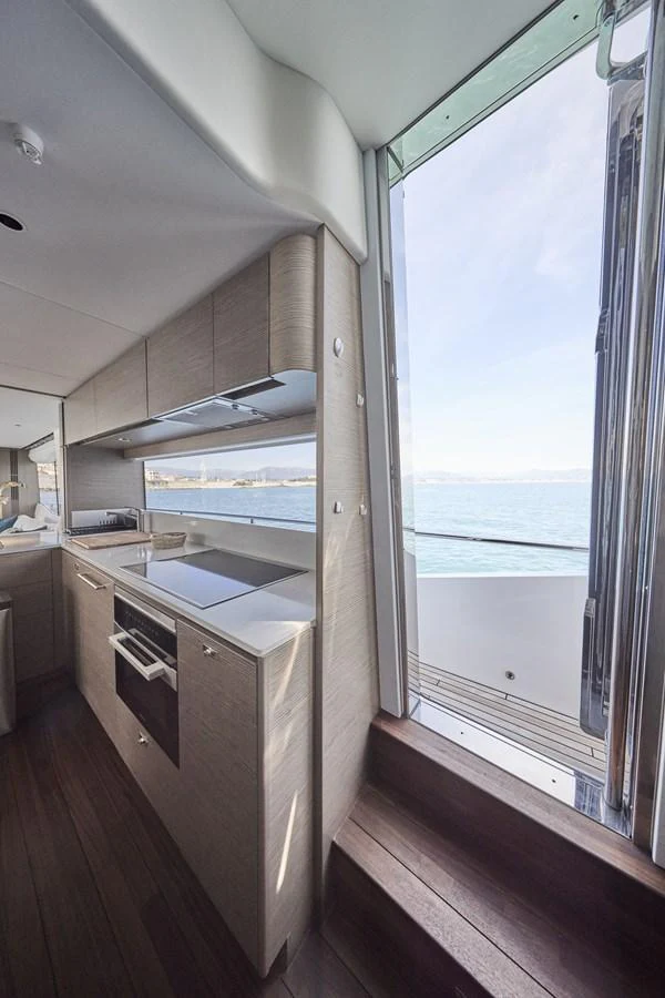 The modern galley features sleek cabinetry and a large window offering a stunning view of the sea. aboard POLARIS Yacht for Sale