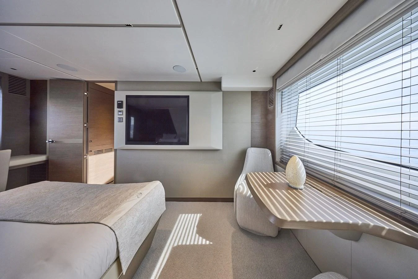 The stateroom features a comfortable bed, a flat-screen TV, and a seating area with a table by the window. aboard POLARIS Yacht for Sale