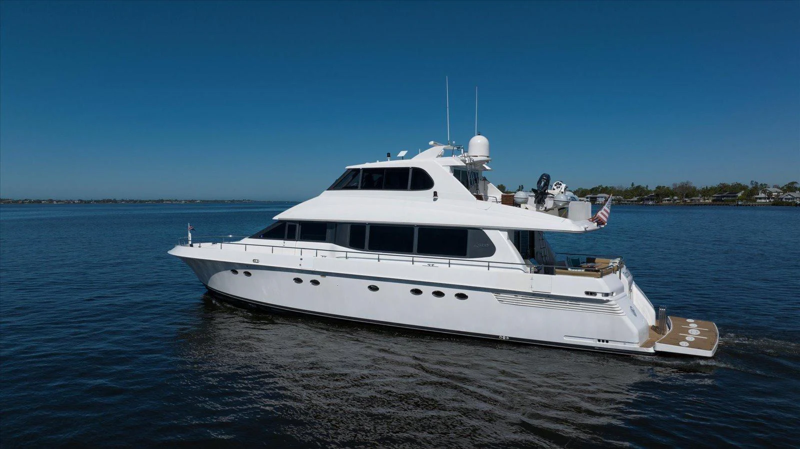 A sleek white yacht glides gracefully on calm waters under a clear blue sky. aboard OCTOPI Yacht for Sale