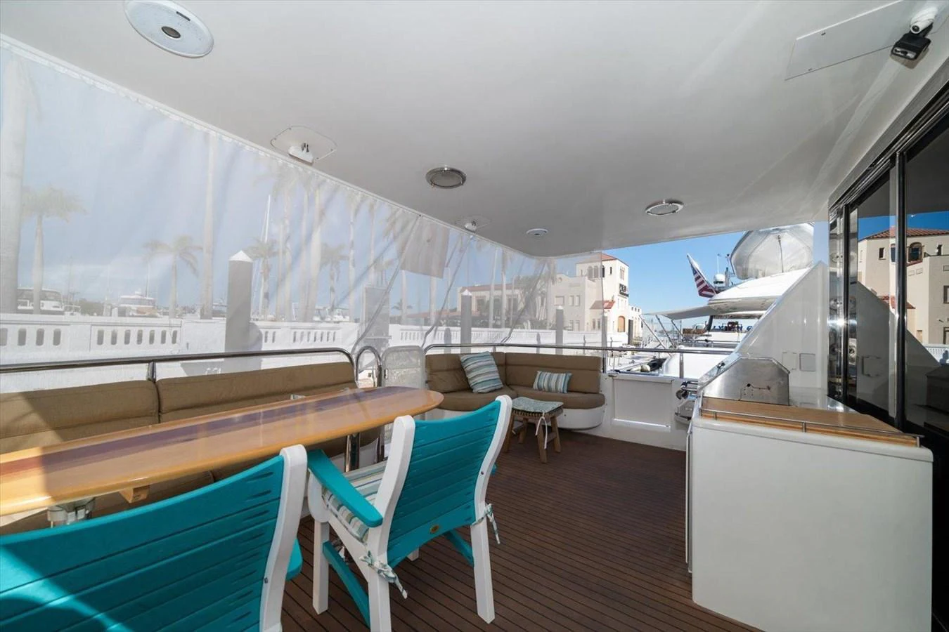 The aft deck features a spacious seating area with a dining table and turquoise chairs, perfect for alfresco dining. aboard OCTOPI Yacht for Sale