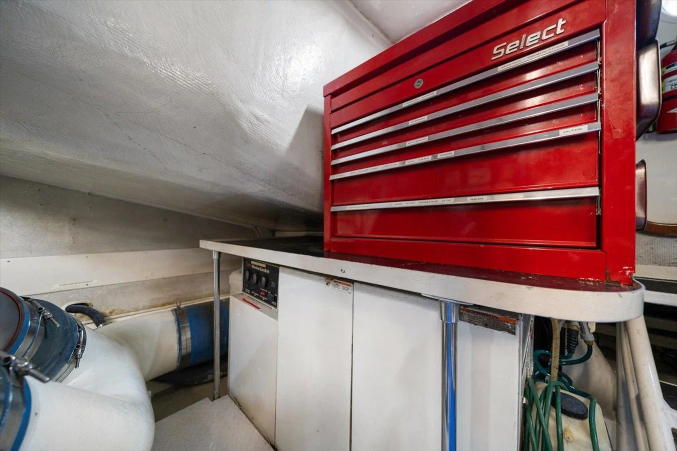 The image showcases the engine room with a prominent red tool chest and various mechanical components. aboard OCTOPI Yacht for Sale