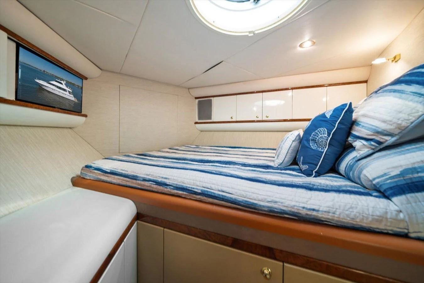 A cozy cabin with a comfortable bed adorned with striped bedding and decorative pillows. aboard OCTOPI Yacht for Sale