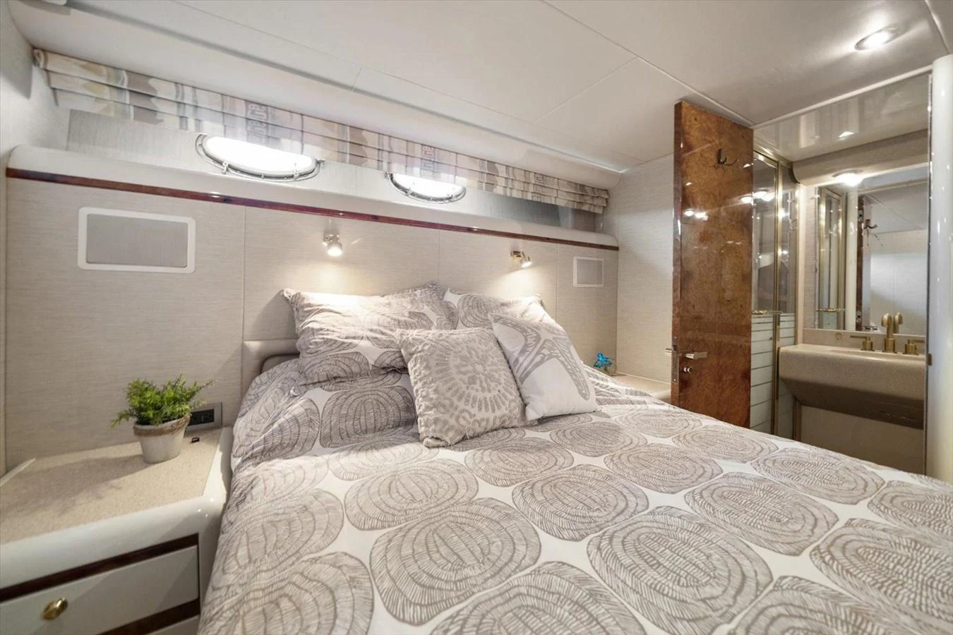 The stateroom features a comfortable bed with elegant bedding and ample natural light from the portholes. aboard OCTOPI Yacht for Sale