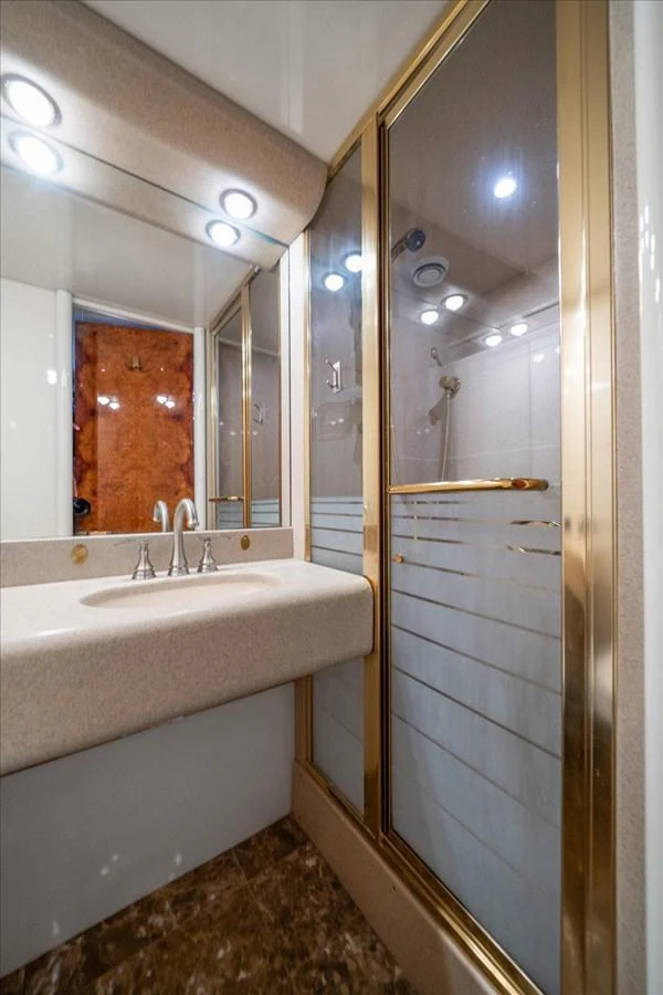 A luxurious yacht bathroom with a modern sink and a glass-enclosed shower. aboard OCTOPI Yacht for Sale