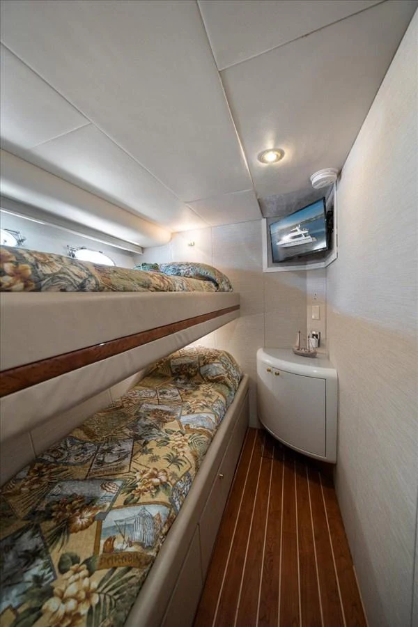 The guest cabin features cozy bunk beds with a small TV and a compact storage unit. aboard OCTOPI Yacht for Sale