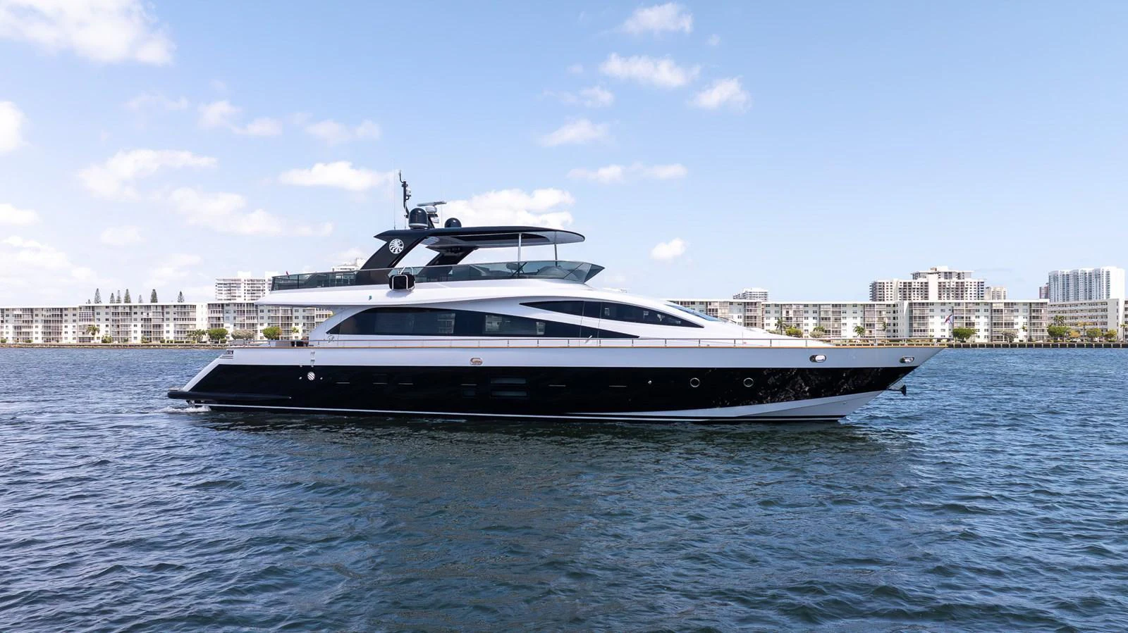 A sleek and modern yacht glides gracefully on calm waters with a cityscape in the background. aboard SEA METRI V Yacht for Sale