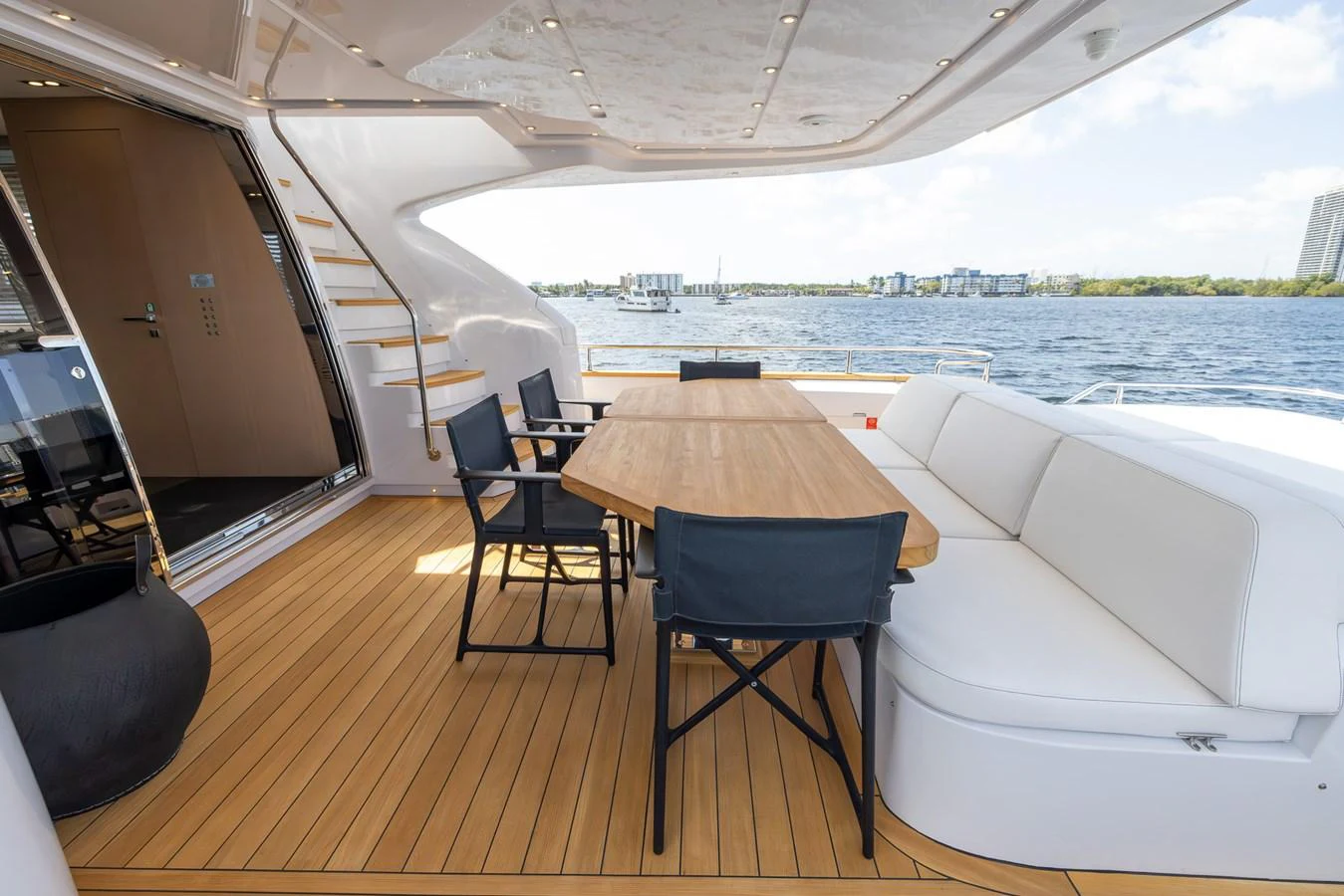The aft deck features a stylish dining area with a wooden table and comfortable seating, perfect for enjoying meals with a view of the water. aboard SEA METRI V Yacht for Sale
