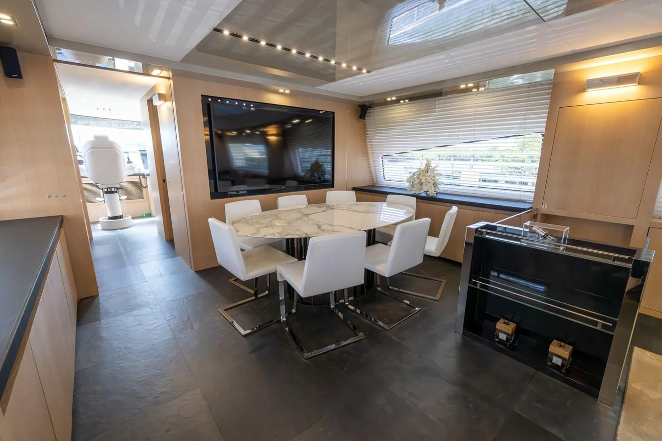 The yacht's dining area features a modern table with white chairs, complemented by a large flat-screen TV and ample natural light. aboard SEA METRI V Yacht for Sale