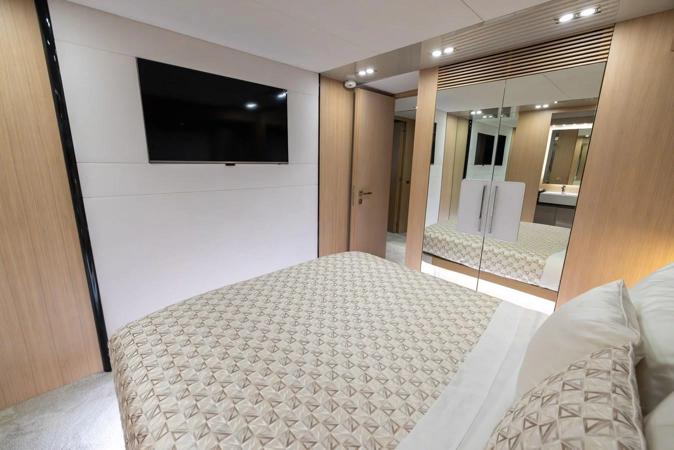 A luxurious stateroom featuring a large bed, mirrored closet, and a wall-mounted TV. aboard SEA METRI V Yacht for Sale