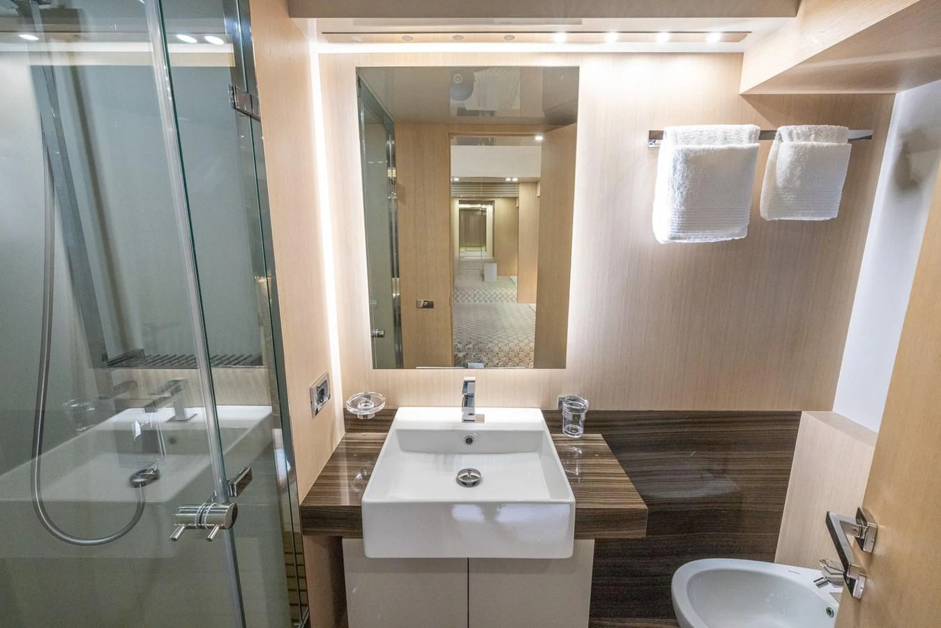 A modern yacht bathroom featuring a sleek sink, glass shower, and elegant wood accents. aboard SEA METRI V Yacht for Sale