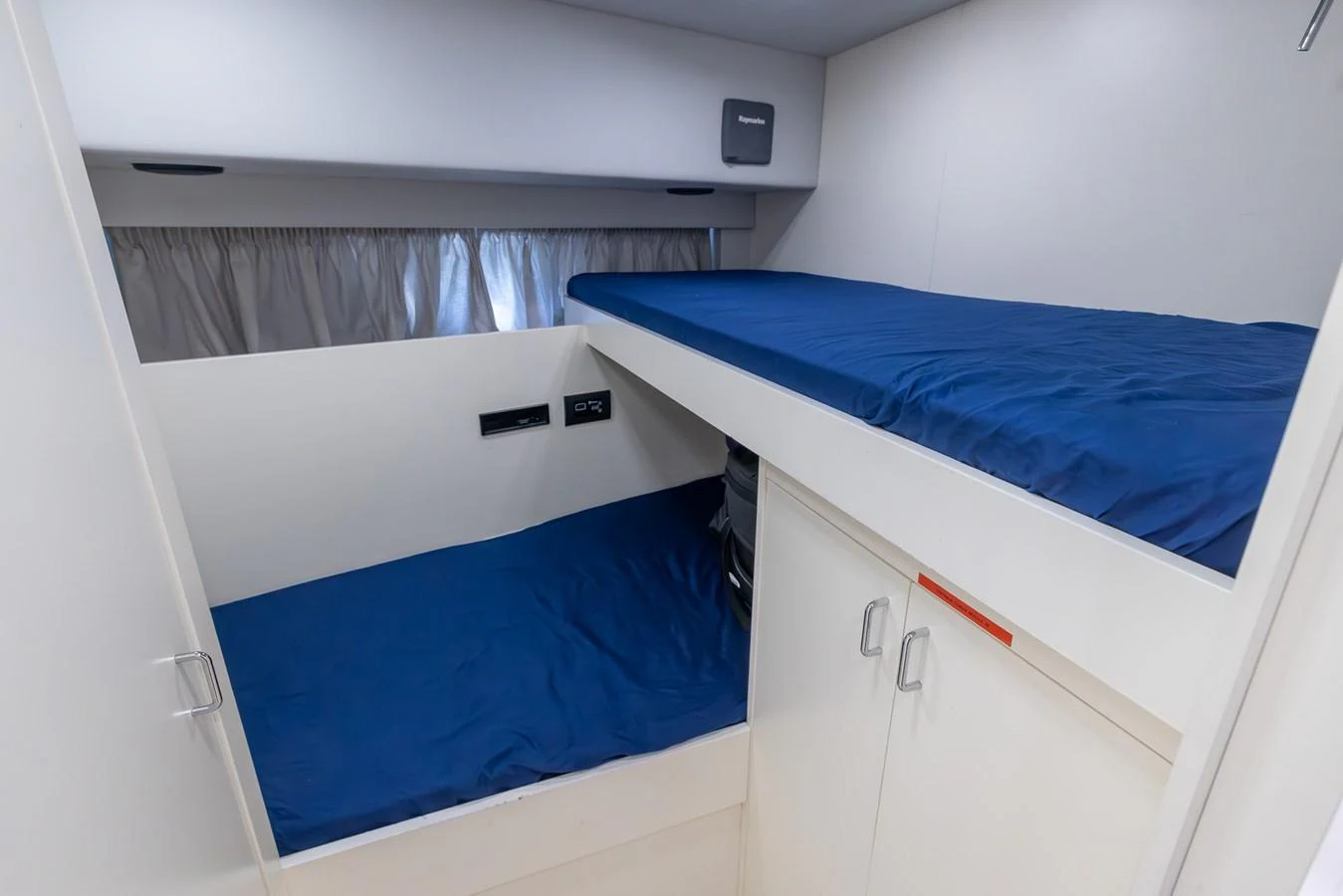 This image showcases a cozy bunk cabin with blue bedding and ample storage space. aboard SEA METRI V Yacht for Sale