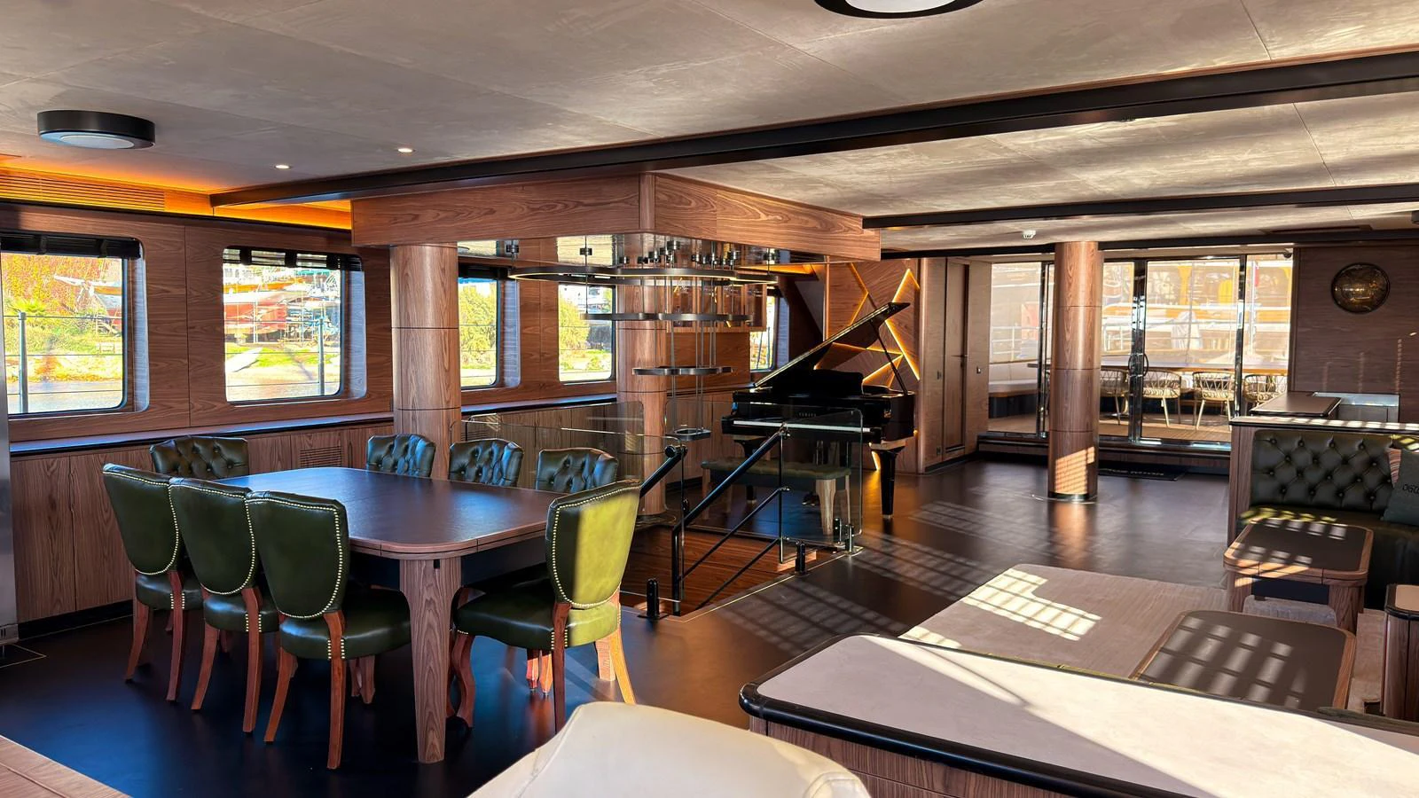 The salon features elegant dining and lounging areas with a grand piano, creating a sophisticated ambiance. aboard OGUZ KHAN Yacht for Sale