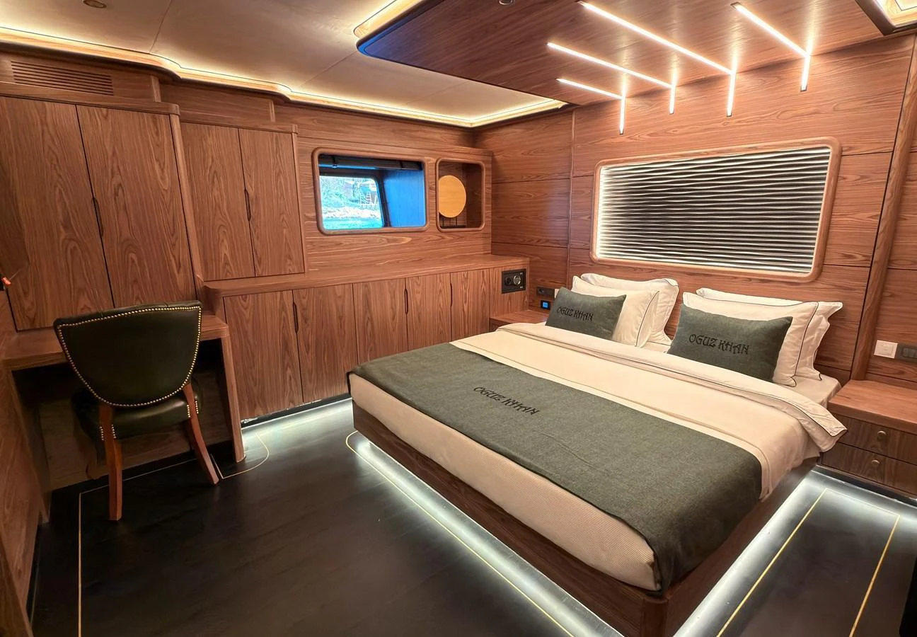 A luxurious stateroom featuring a large bed, elegant wood paneling, and modern lighting. aboard OGUZ KHAN Yacht for Sale