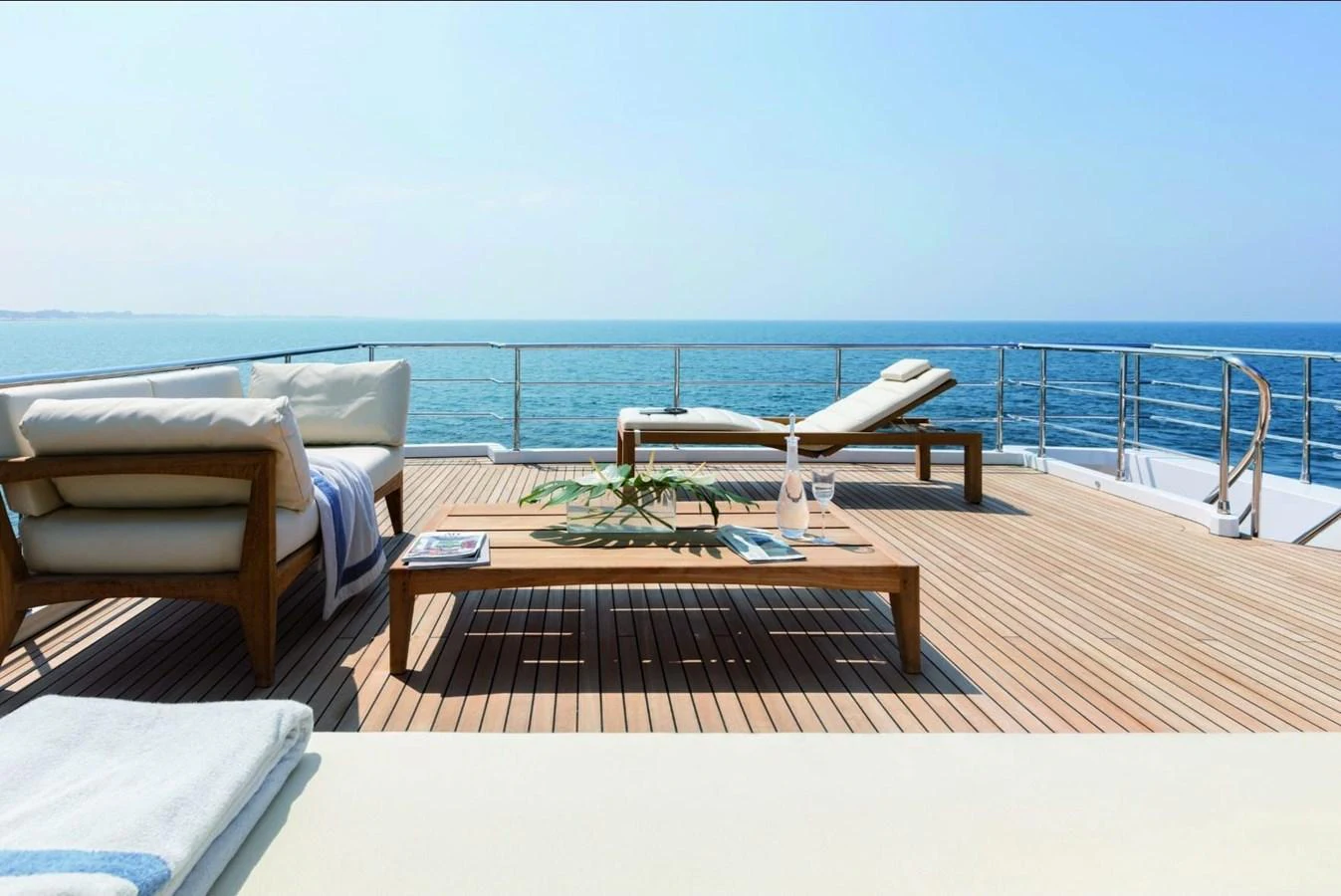 a lounge chair and a table on a deck overlooking the ocean aboard SHABBY OF THE SEAS Yacht for Sale