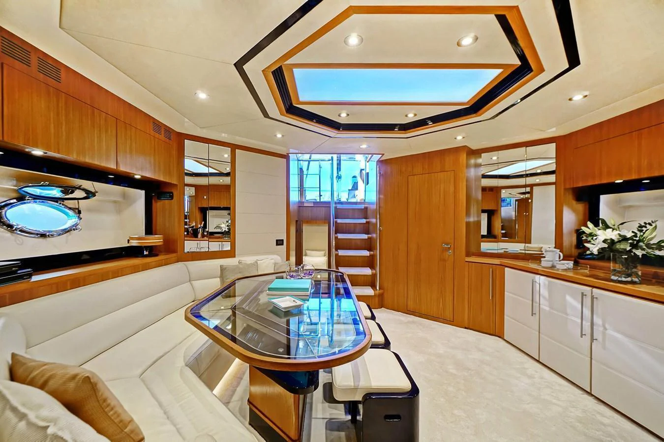 The yacht's salon features a luxurious seating area with a glass-top table and elegant wood finishes. aboard RIVA 72' Yacht for Sale
