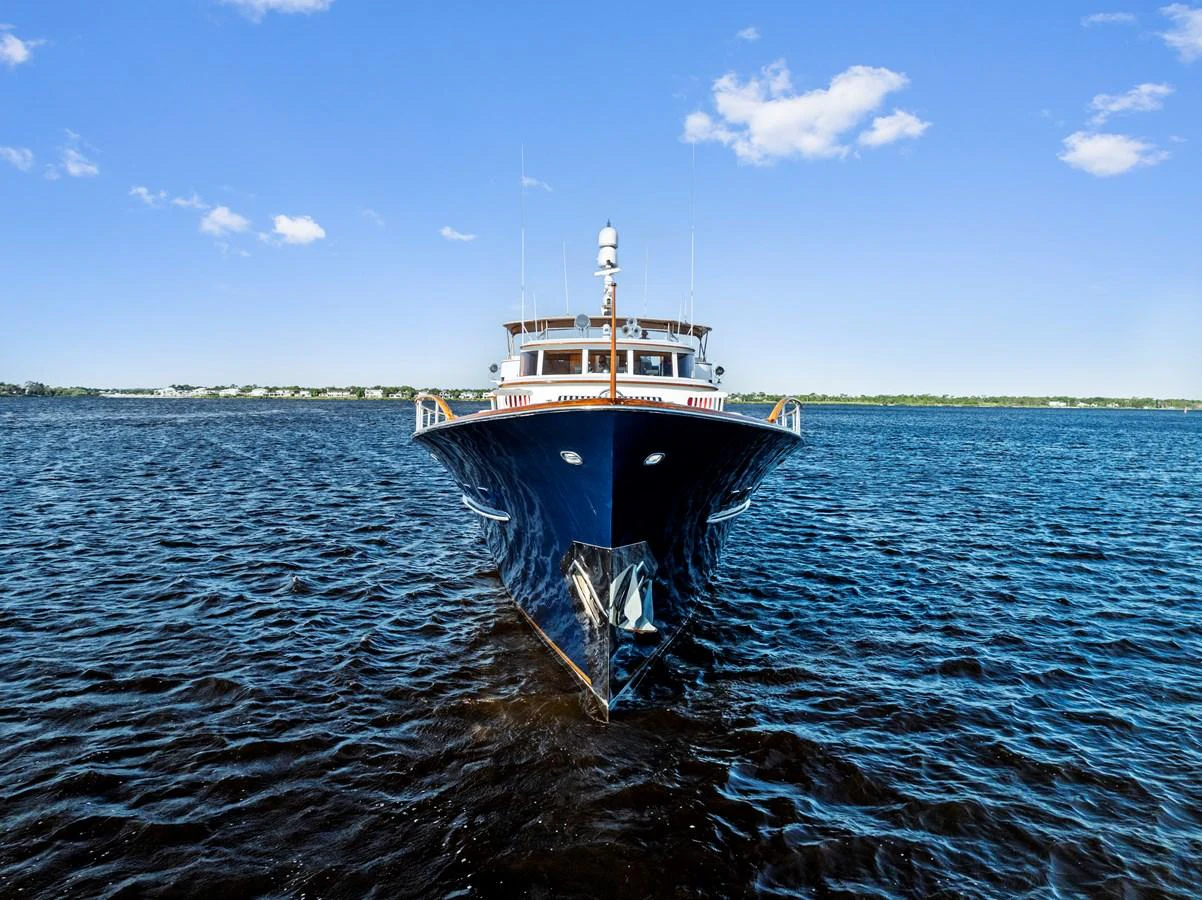 A sleek yacht is captured head-on, cutting through the serene waters under a clear blue sky. aboard CHANTICLEER Yacht for Sale