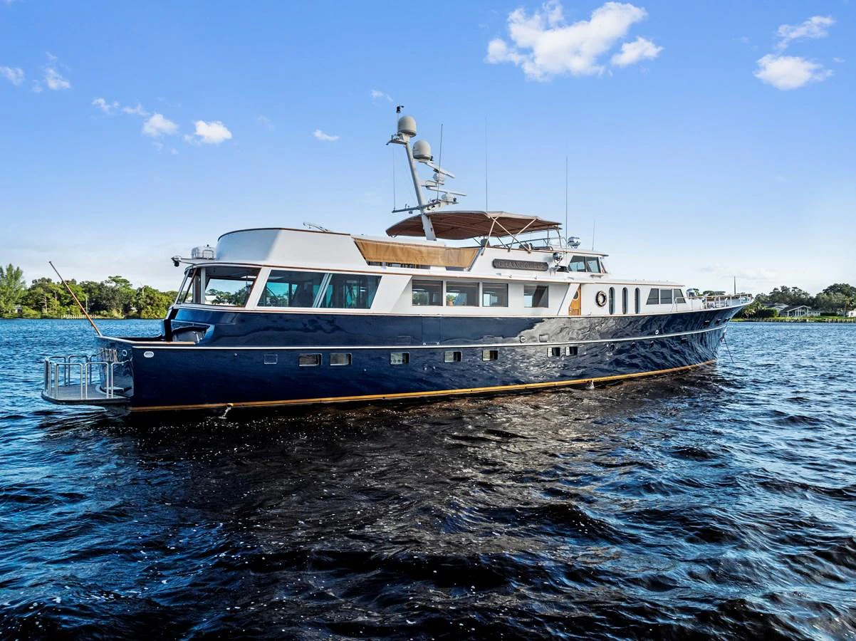 A classic yacht with a sleek blue hull cruising on calm waters under a clear blue sky. aboard CHANTICLEER Yacht for Sale