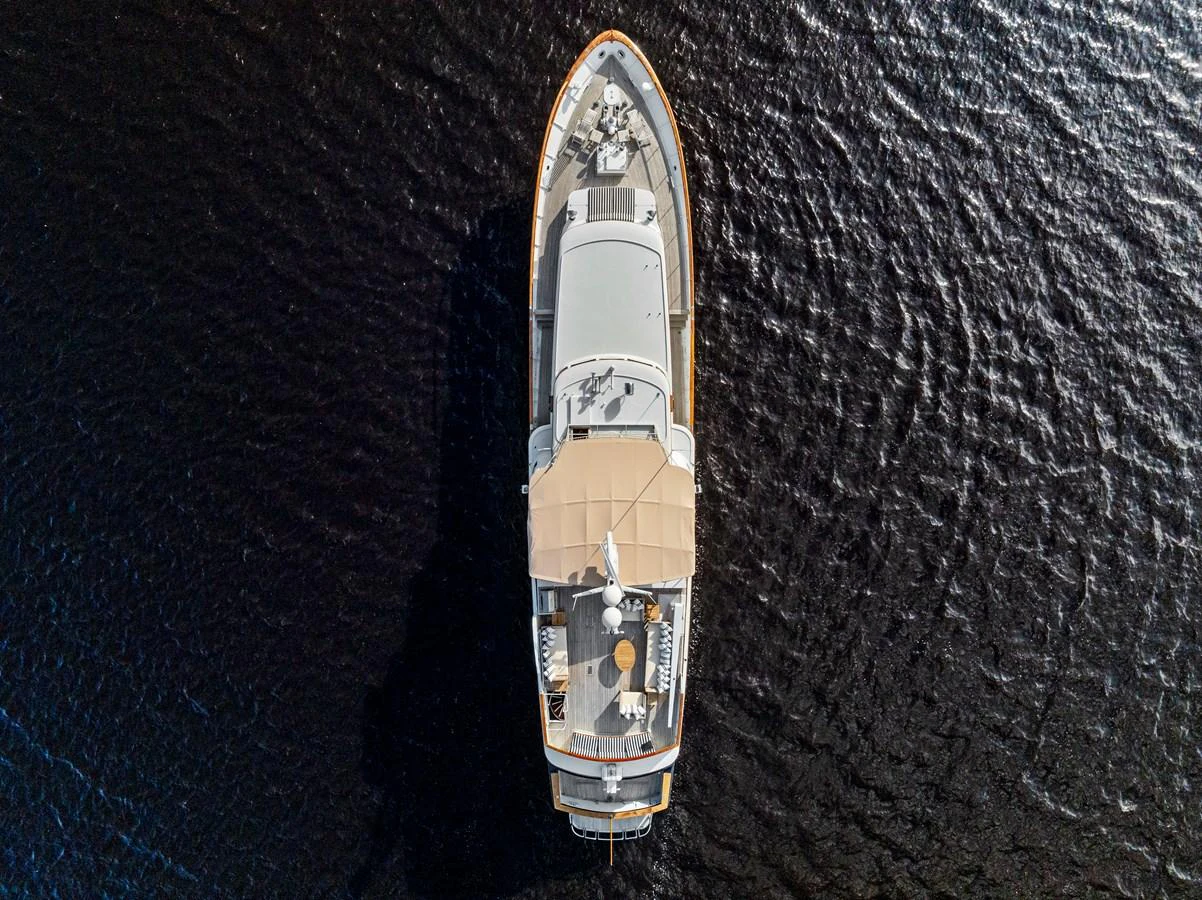 Aerial view of a yacht cruising on dark waters, showcasing its sleek design and spacious deck areas. aboard CHANTICLEER Yacht for Sale