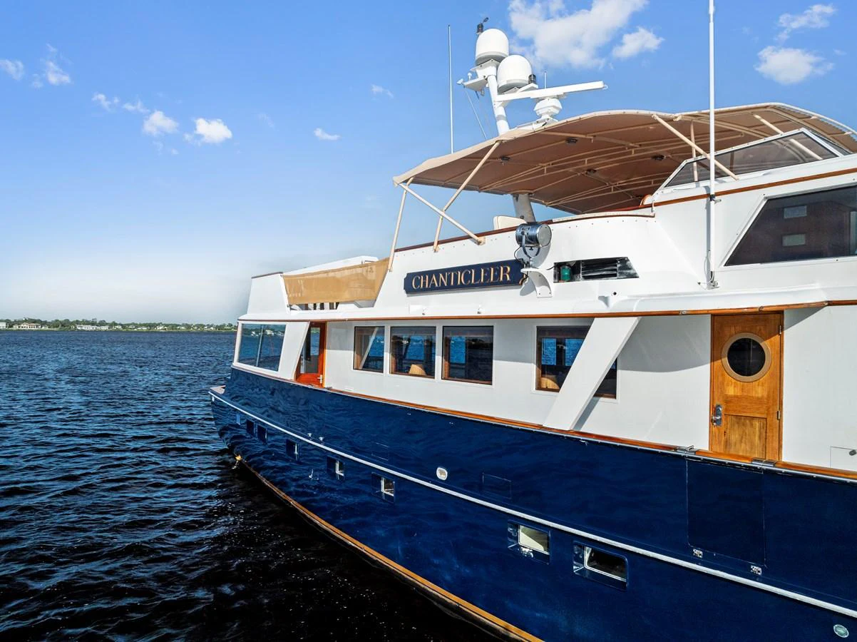 A classic yacht with a sleek blue hull and white superstructure cruising on calm waters under a clear sky. aboard CHANTICLEER Yacht for Sale