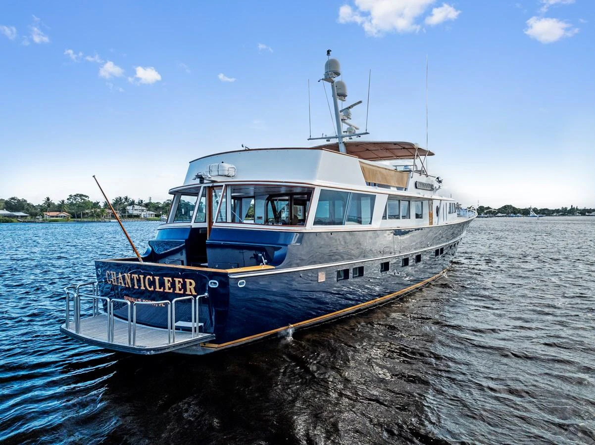 A classic yacht with a sleek blue hull cruising on calm waters under a clear sky. aboard CHANTICLEER Yacht for Sale
