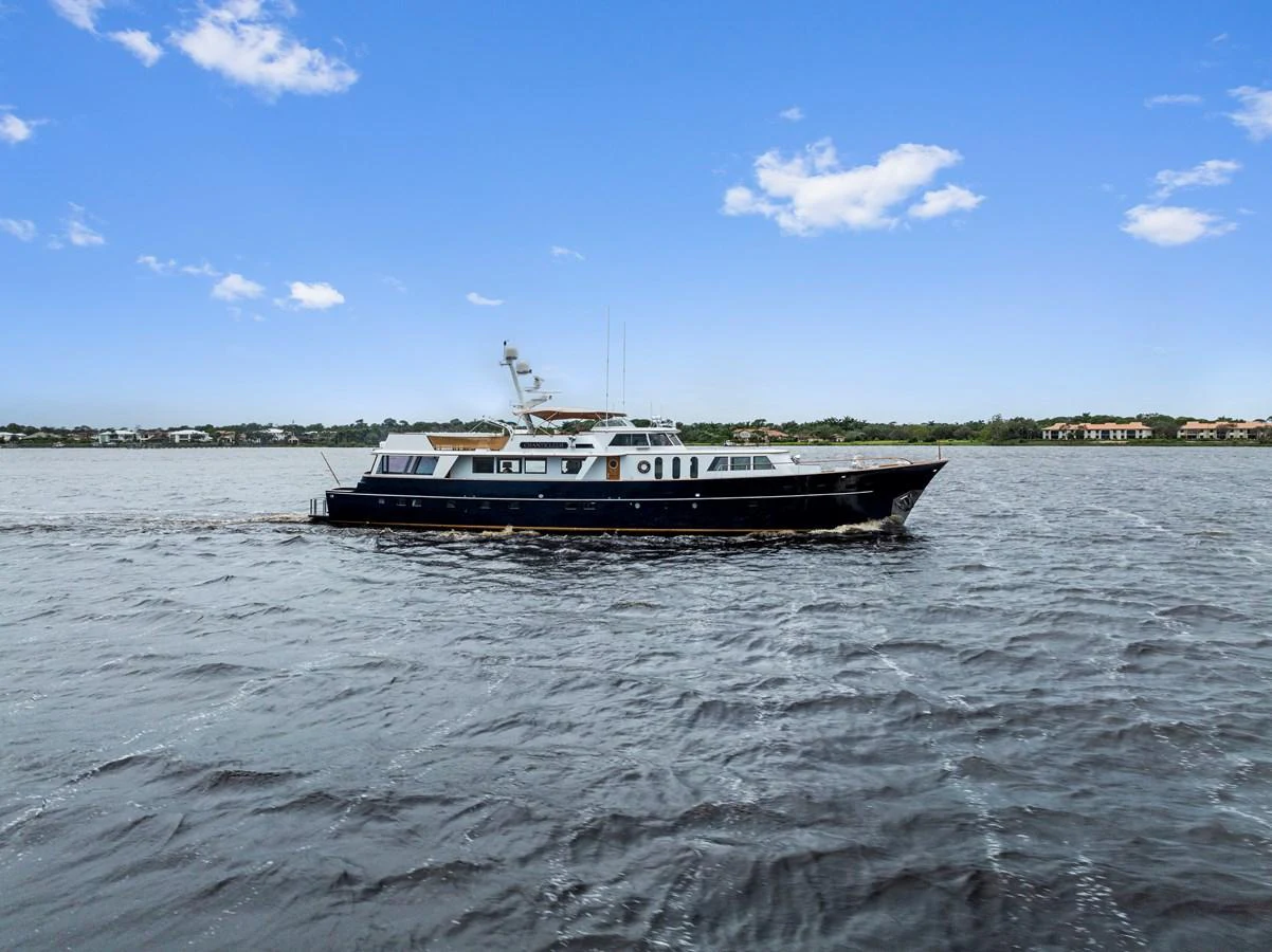 A sleek yacht glides smoothly on the water under a clear blue sky. aboard CHANTICLEER Yacht for Sale
