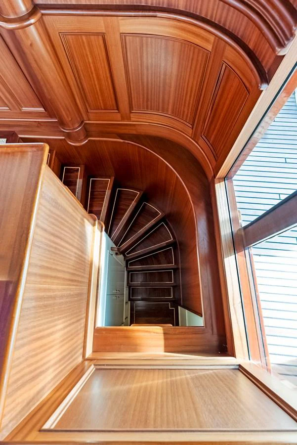 A beautifully crafted wooden staircase with elegant paneling and natural light streaming in. aboard CHANTICLEER Yacht for Sale