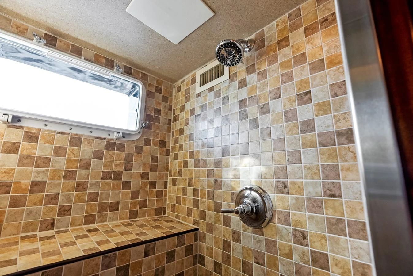 The yacht's bathroom features a tiled shower with a built-in bench and modern fixtures. aboard CHANTICLEER Yacht for Sale