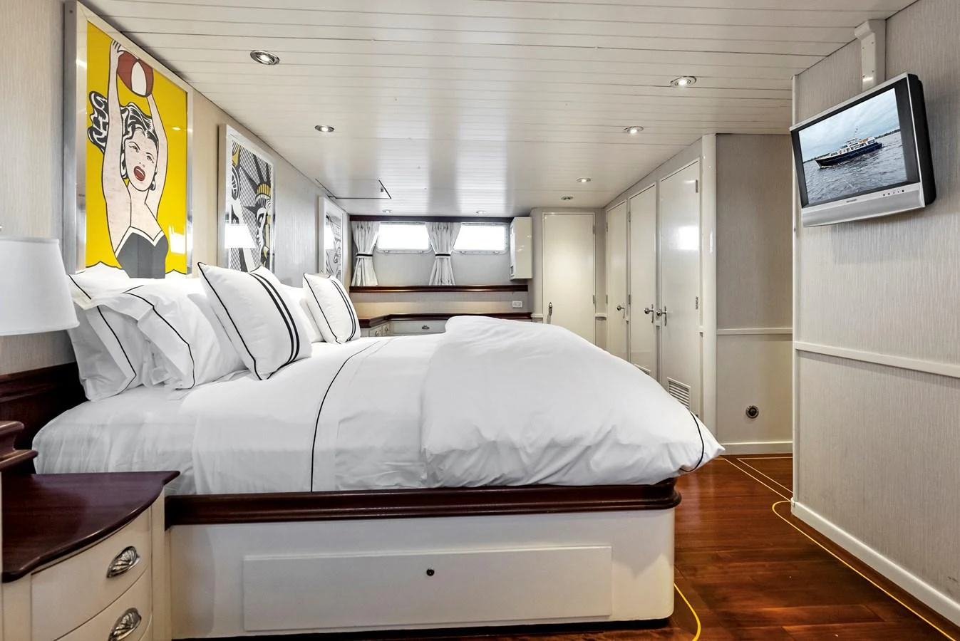 The stateroom features a comfortable bed with crisp white linens and modern artwork on the walls. aboard CHANTICLEER Yacht for Sale