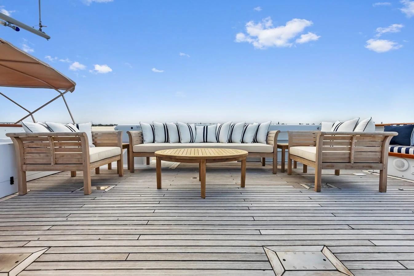 The sundeck features a spacious seating area with comfortable wooden furniture and a round table, perfect for relaxation and socializing. aboard CHANTICLEER Yacht for Sale
