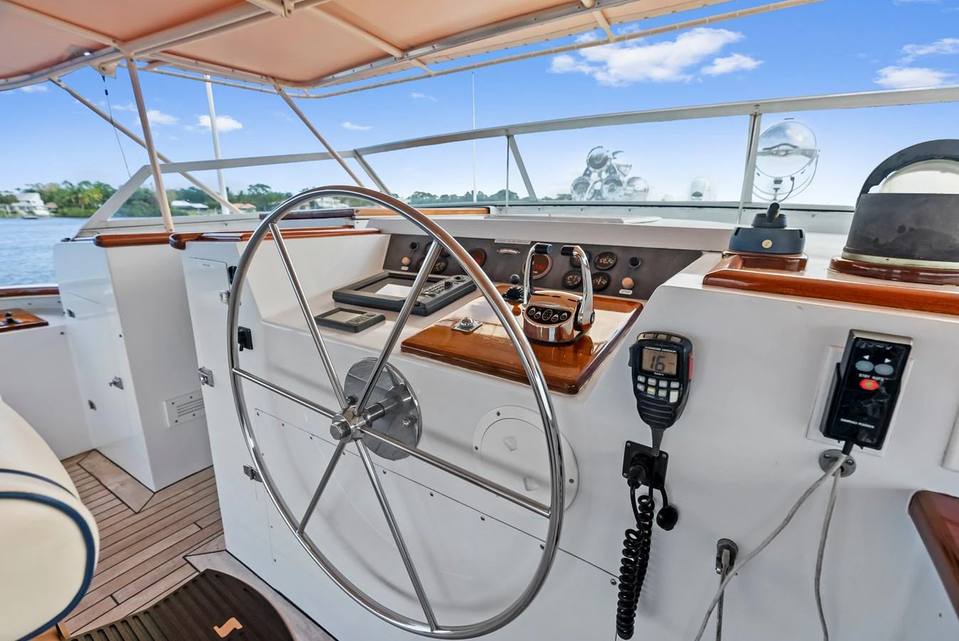 The helm station features a large steering wheel and modern navigation equipment, set against a backdrop of serene waters. aboard CHANTICLEER Yacht for Sale